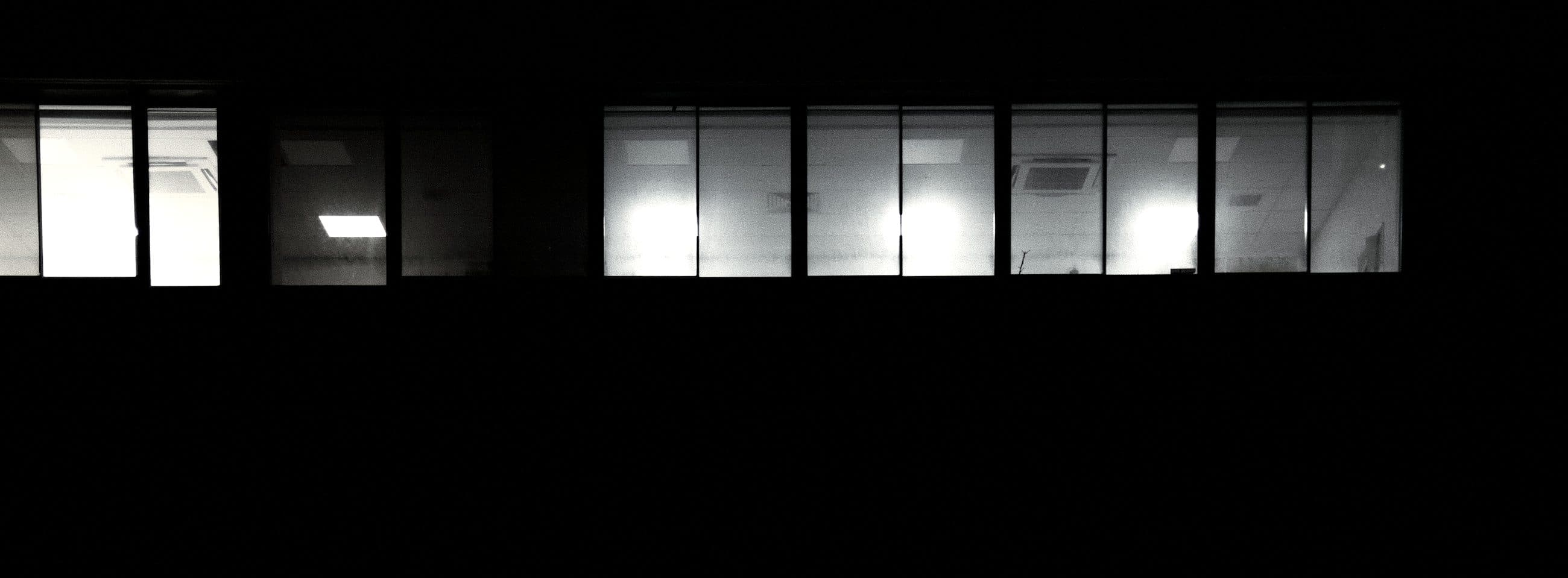 Faixa de janelas de escritório iluminadas contra o escuro